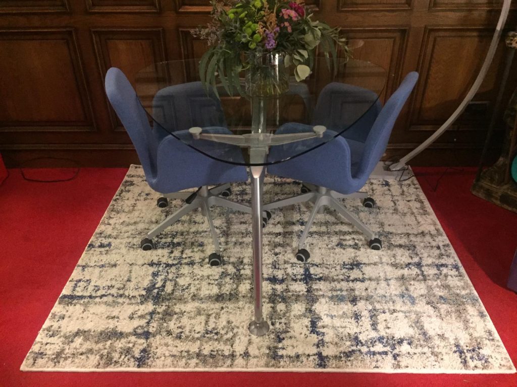 Imagen de una estancia elegante con una alfombra bajo mesa y sillas