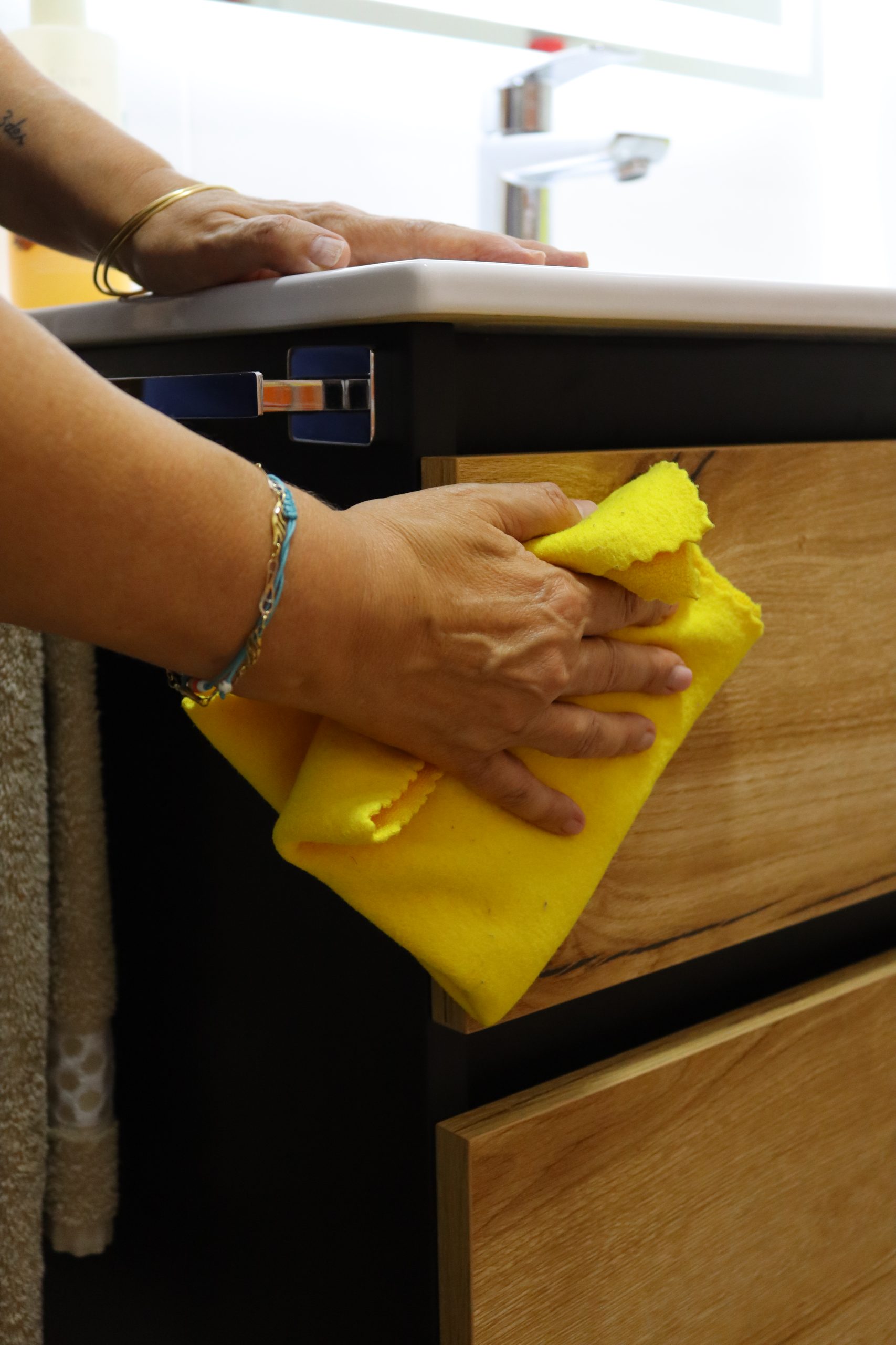 Primer plano de la mano de una persona limpiando un mueble de baño