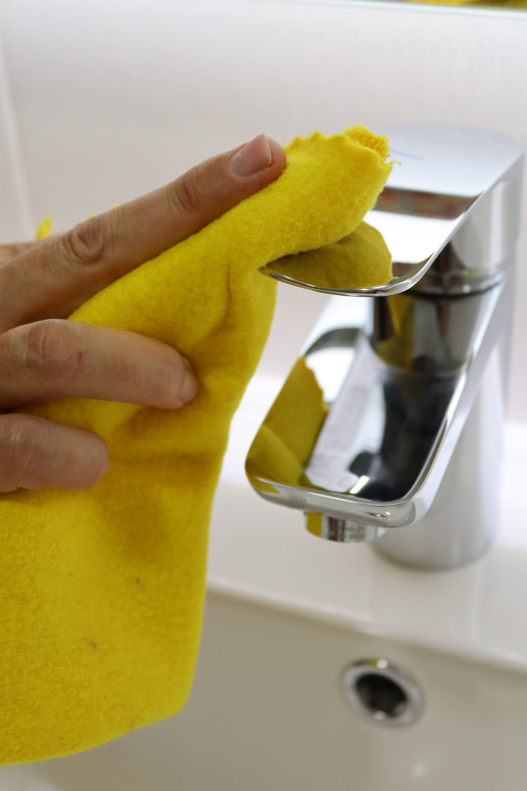 Primer plano de la mano de una persona limpiando el grifo de un lavabo